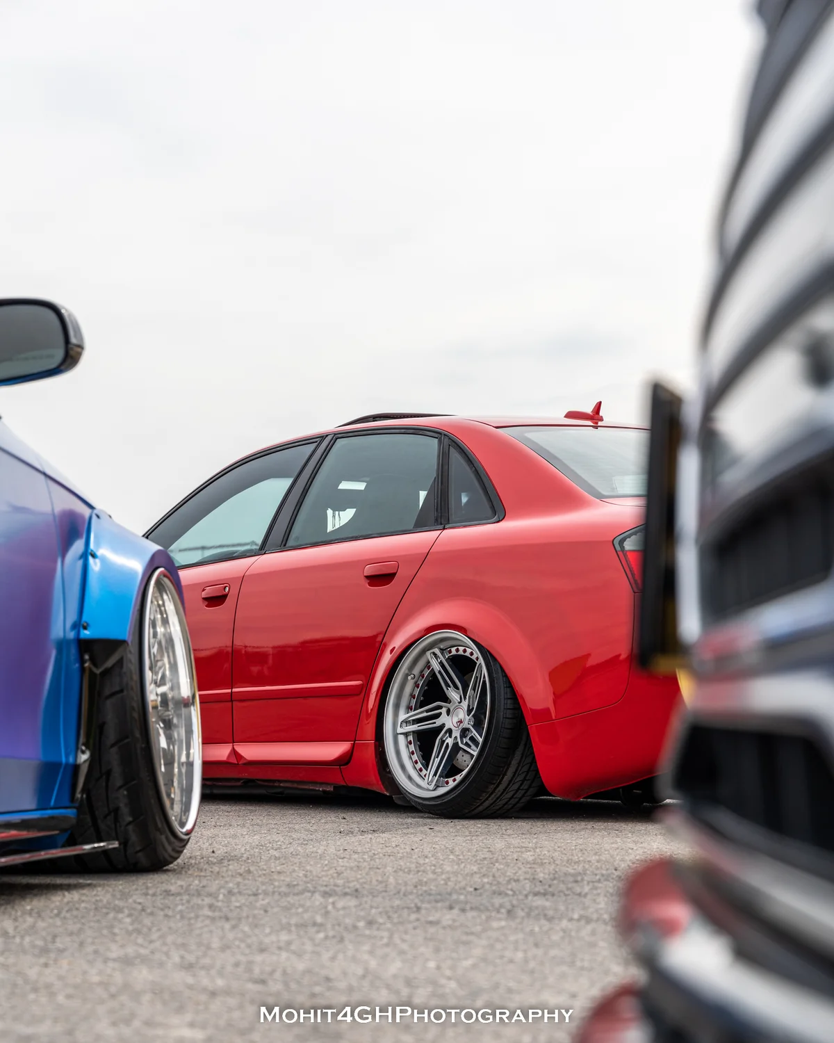 Side view of a lowered red Audi between show cars