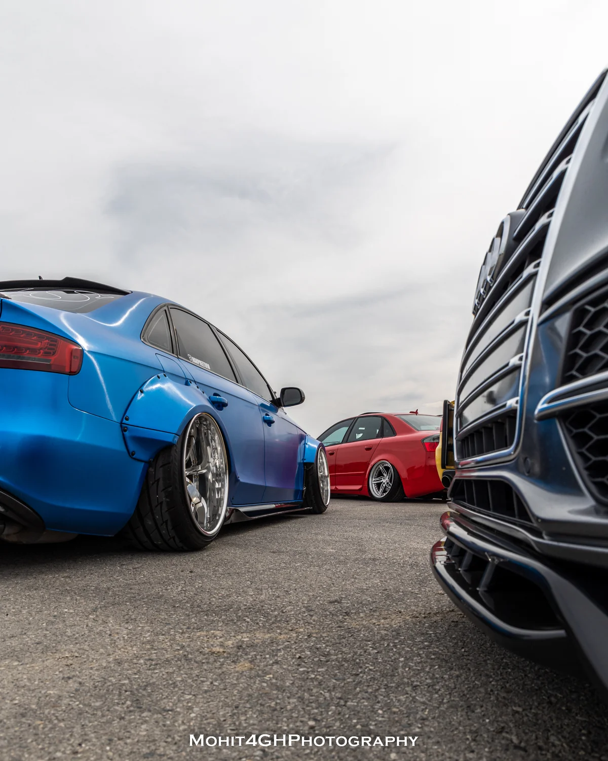 Blue wide-body Audi with a red Audi in the background